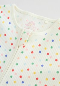 Body pour bébé blanc avec texture côtelée et pois multicolores, doté d'une fermeture éclair à l'avant et d'un col rond.