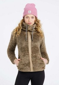 Bruine fleece jack met hoge kraag en ritssluiting, voorzien van crèmekleurige details, twee zijzakken en gedragen met een roze beanie.