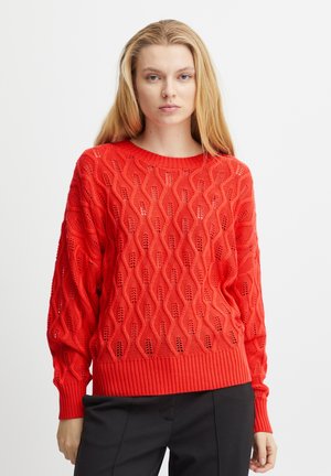 Maglione rosso lavorato a maglia con un motivo a onde, dotato di polsini e orlo a costine. Realizzato in un materiale leggero, ha una vestibilità ampia e un design strutturato.