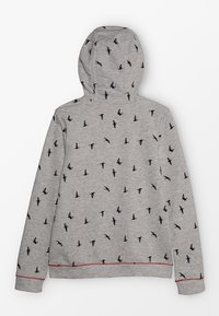 Grå huvtröja med svart fågelmönster genom hela plagget, med en mjuk textur och röda kontrastsömmar vid nederkant och ärmar.