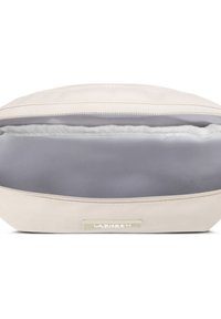 Bežová taška na zips s hladkým vonkajším povrchom a mäkkým šedým podšívkom. Má štítok na prednej strane a jednoduchý, obľúbený tvar.