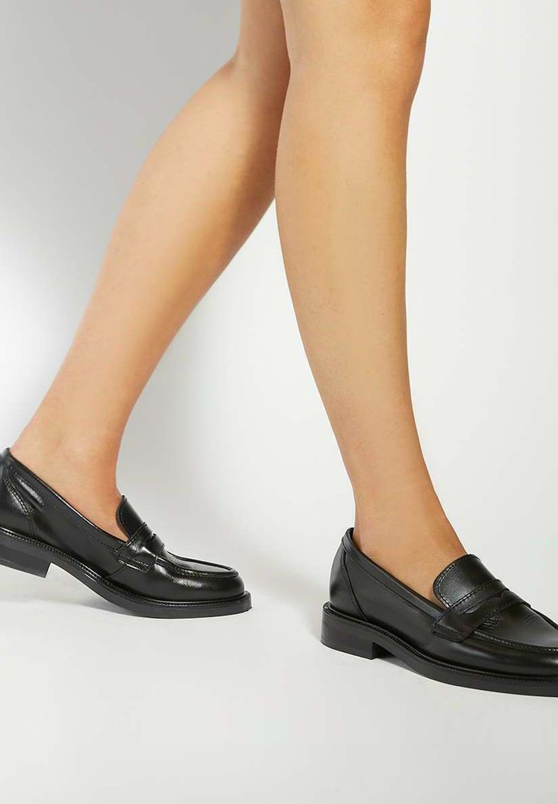 Black leather loafers with a smooth texture, low block heel, and decorative stitching on the vamp. Minimalist design, suitable for formal wear.