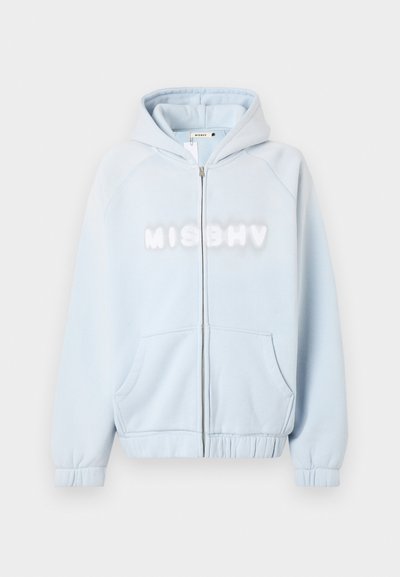 Gaiši zila ar rāvējslēdzēju kapuce, izgatavota no mīksta materiāla. Priekšpusē ir balta "MISBHV" zīme, raglán piedurknēm un priekšējiem kabatām.