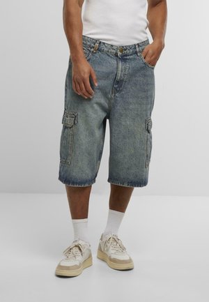 Shorts cargo en denim bleu clair, dotés de poches latérales et d'une coupe décontractée, avec des ourlets retroussés et une fermeture à bouton classique.