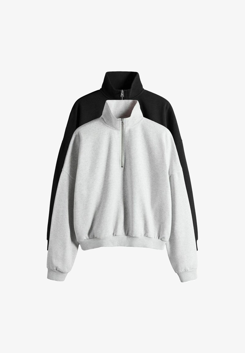 Kaks poollukuga dressipluusi laotud, üks helehall ees ja üks must taga, mõlemal kõrge krae ning soonikutega varrukasääred ja alumised ääred.