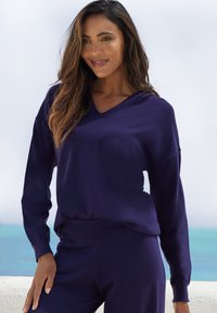 Top blu navy a V con maniche lunghe, realizzato in tessuto morbido, abbinato a pantaloni coordinati. L'insieme presenta una vestibilità comoda e un bordo a coste.