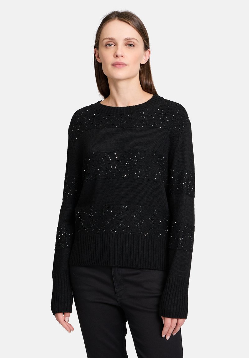 Pull en tricot noir avec des rayures horizontales et des accents métalliques, un col rond côtelé et des manches longues.