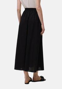 Gonna maxi nera con elastico in vita, caratterizzata da una silhouette fluida e un tessuto leggero per il massimo comfort. Orlo semplice, senza fantasie.