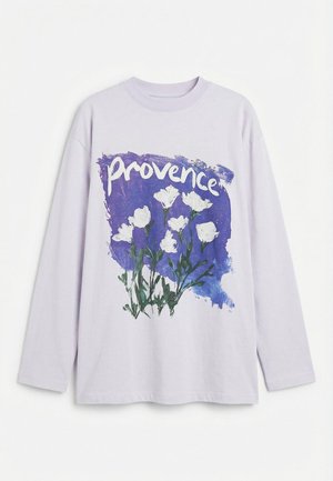 Lavendel langermet skjorte med en lilla penselstrøk, hvite blomster og ordet "provence" trykt over brystet.