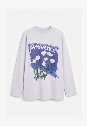 Lavendel langermet skjorte med en lilla penselstrøk, hvite blomster og ordet "provence" trykt over brystet.
