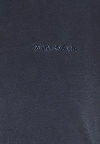 Mörkblå stickad sweatshirt med en tonad broderad logotyp "Marc O'Polo" på övre vänstra sidan. Slät textur, avslappnad passform.