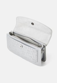 Sac en simili cuir argenté avec logo en relief, fermeture à pression magnétique et compartiments intérieurs. Texture lisse avec une forme structurée.