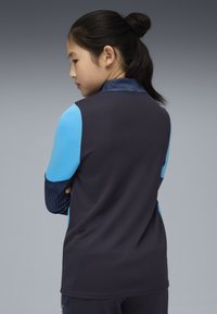 Maglia sportiva nera con accenti blu, caratterizzata da un motivo testurizzato sulle maniche e sul colletto, vista da dietro.