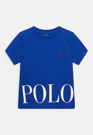 Blaues kurzärmeliges T-Shirt mit großem weißem "POLO"-Schriftzug am unteren Rand und kleinem roten, gestickten Pferdelogo auf der oberen linken Brustseite.