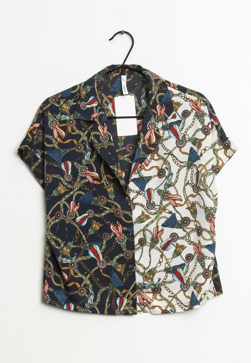 Blusa a maniche corte con un design a spacco: un lato presenta un motivo floreale scuro, l'altro un motivo a catena chiara, entrambi con colori vivaci.