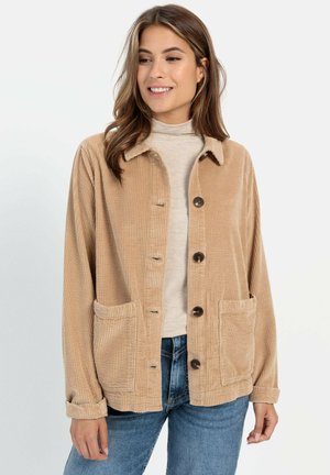 Beige corduroy jas met een kraag, knoopsluiting en twee voorzakken. Zachte textuur en relaxte pasvorm, met opgerolde mouwen en bruine knopen.