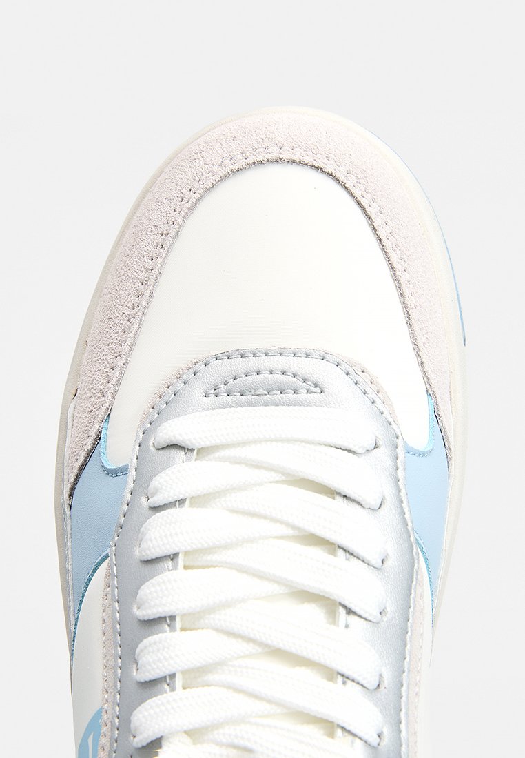 Zapatilla con cuero blanco y acentos azul claro, con puntera suave de gamuza, cordones redondos y suela texturizada.