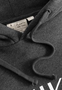 Donkergrijze hoodie stof met een zachte textuur, voorzien van trekkoorden en een label met merk- en productdetails.