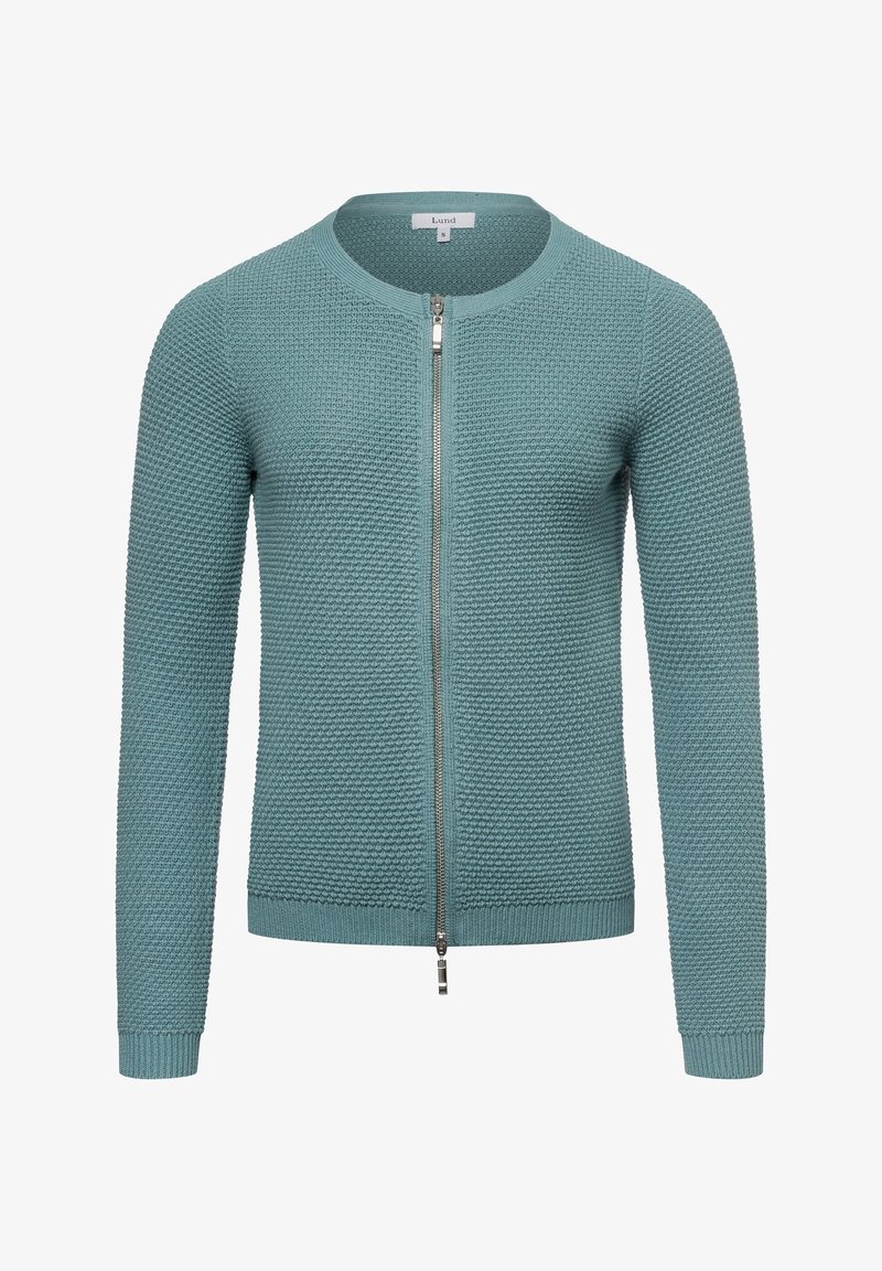 Pletená cardigan s kruhovým zipem v tóne tealu, s texturovaným vzorem, kulatým výstřihem a žebrovanými manžetami a spodním lemem. Zip sahá až k límci.