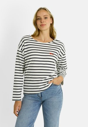 Top de manga larga a rayas en blanco con franjas horizontales negras; presenta un diseño de corazón rojo cerca del pecho. Material de algodón suave, ajuste relajado.