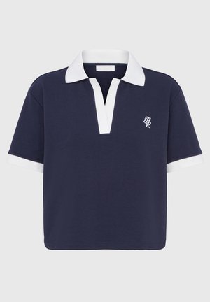 Polo shirt navy avec un col et des accents de manches blancs, présentant un design de patte de boutonnage et un logo brodé sur le côté gauche. Matériau en coton.