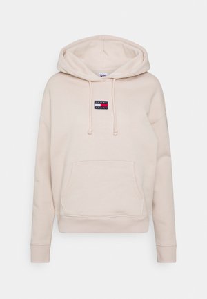 Beżowa bluza z kapturem typu pulower, z kieszenią z przodu, sznurkiem w kapturze oraz małym prostokątnym logo Tommy Jeans w kolorach czerwonym, białym i granatowym na środku klatki piersiowej.