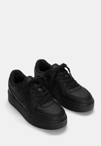 Czarne sneakersy wykonane z syntetycznej skóry, z teksturowaną powierzchnią, okrągłym noskiem, płaską podeszwą oraz sznurowanym fasonem z perforowanymi akcentami.