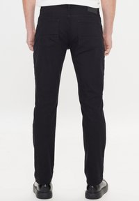 Černé bavlněné kalhoty s rovnými nohavicemi, vybavené dvěma zadními kapsami a jemnými šicími detaily. Hladká textura a minimalistické kovové doplňky.