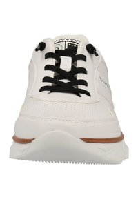 Hvide sneakers med sorte snørebånd, perforeret overdel og en tekstureret hvid sål. Har en brun accent omkring sålens kant.