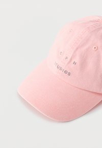 Ανοιχτό ροζ καπέλο μπέιζμπολ με κεντημένο κείμενο «CPH STUDIOS» στο μπροστινό μέρος, πάνω σε απλό λευκό φόντο.