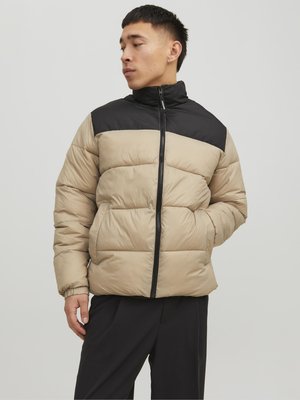 Giacca imbottita beige con sezione superiore nera, dotata di un colletto alto, chiusura a zip e trapuntatura orizzontale. Il materiale appare liscio e morbido.