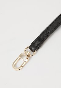 Sangle noire texturée en matériau synthétique avec un clip en métal doré pour attacher, présentant un mécanisme de fermeture sécurisé.