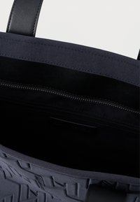 Saco de coqueiro azul com exterior de tecido texturizado, alças em pele preta e bolso interior com fecho. Completamente forrado com uma superfície suave.