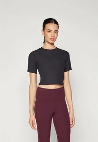 Svart kortärmad t-shirt i ett mjukt tyg. Matchad med högmidjade vinröda leggings med en sömlös design.