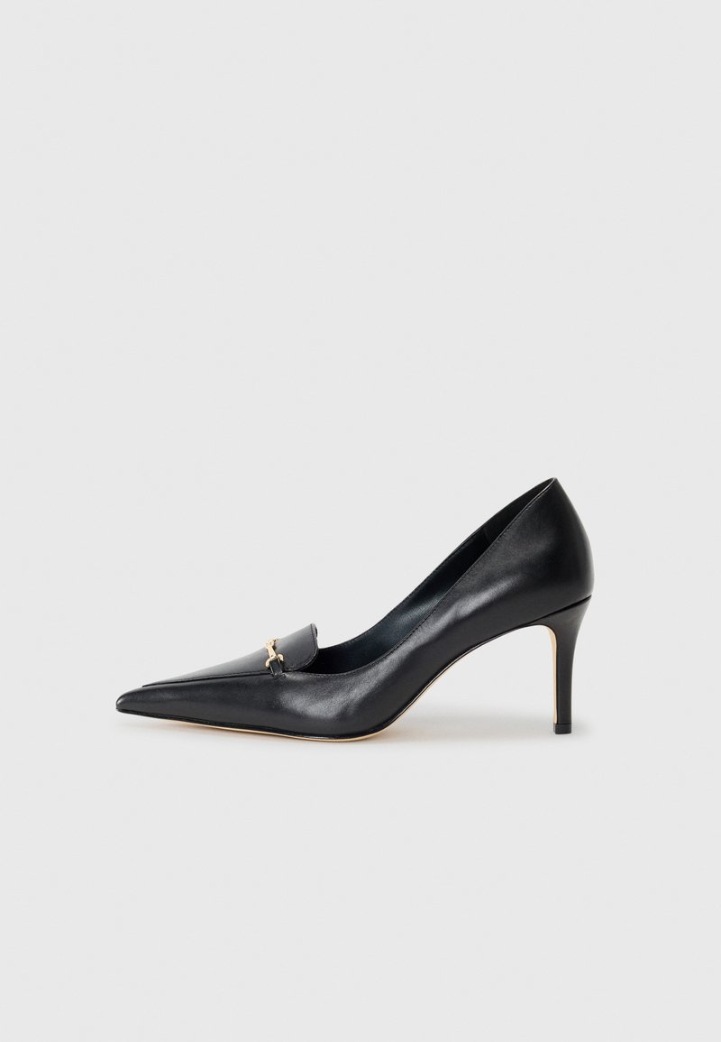 Svart lærpumps med spiss tå, lav vamp og dekorativ gullaccent. Har stiletthæl og glatt tekstur.