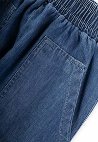 Džínsy s elastickým pásom, s bočnou kapsou a tmavomodrou farbou s jemným, texturovaným povrchom.