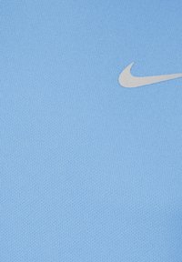 Hele sinine Nike'i kangas, millel on tekstureeritud pind. Esiplaanil on valge Nike'i logo, mis on paigutatud vasakule küljele.