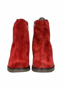 Bottines en suédine rouge avec une texture lisse, bout rond et petit talon ; dotées de fermetures éclair de chaque côté pour un enfilage facile. Semelles noires.