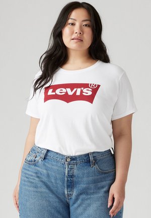 Witte katoenen T-shirt met een groot rood Levi's logo, ronde halslijn en korte mouwen, gecombineerd met lichtblauwe high-waisted jeans.