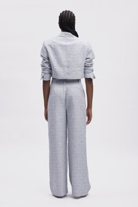 Veste courte gris clair avec des manches roulées et un pantalon large taille haute assorti, présentant un tissu texturé avec des motifs subtils.