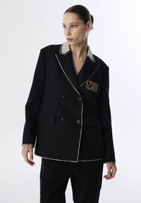 Zwarte dubbelbreasted blazer met witte stiksels, contrasterende zigzagkraag en een patch met "THE LAB." Bevat twee voorkezen.