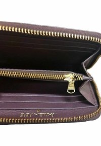 Portefeuille en cuir brun ouvert montrant un compartiment zippé doré, plusieurs emplacements pour cartes et le nom de la marque en relief à l'intérieur.