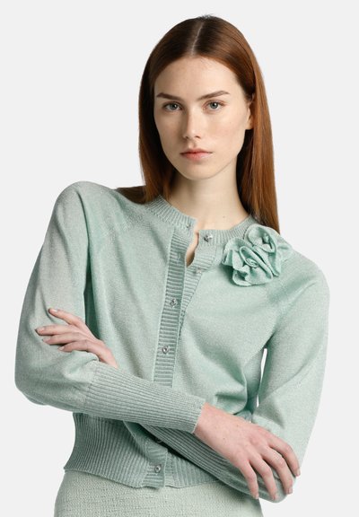 Mintgrüner Cardigan aus strukturiertem Strick. Mit rundem Ausschnitt, Knopfschluss, gerippten Bündchen und einem dekorativen Blumendetail auf der Brust.