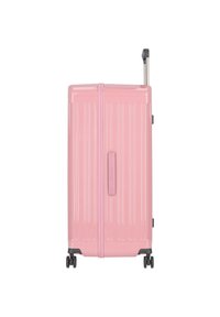 Maleta rígida rosa con ranuras verticales, un asa retráctil y cuatro ruedas para mayor movilidad. Textura suave y forma rectangular compacta.