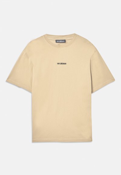 T-shirt en coton beige à manches courtes, coupe décontractée, col rond et un petit logo imprimé en couleur foncée sur la poitrine.