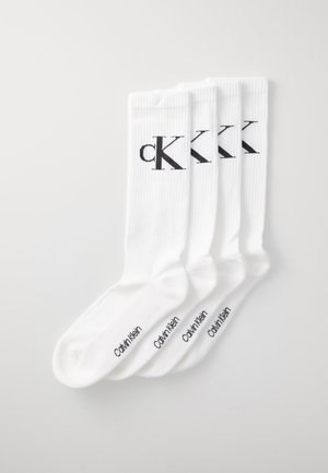 Calcetines blancos de textura acanalada, con el logo en negro "ck" y el texto "Calvin Klein". Paquete de cuatro pares, de longitud estándar.