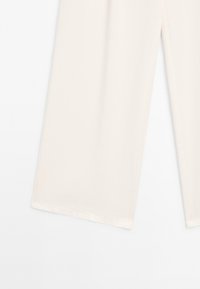 Pantalon large crème en tissu doux, avec une texture lisse, des bords nets et une silhouette décontractée.