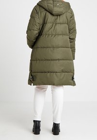 Olivgrüner Puffer-Mantel mit Kapuze, horizontalen Nähten, Seitentaschen und Zugbändern am Saum.