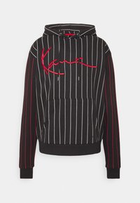 Musta huppari, jossa valkoiset pystysuorat raidat ja punaiset korostukset. Edessä tasku ja punainen kirjailtu "Kanai"-logo.