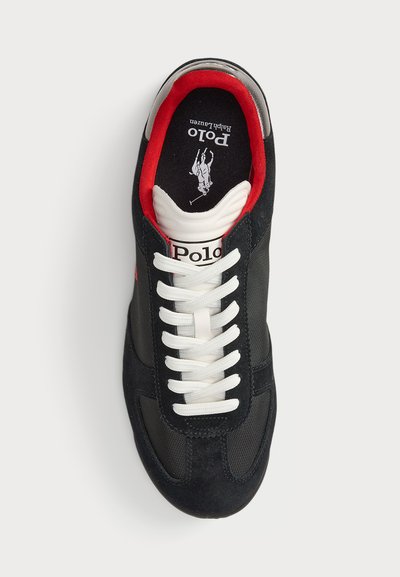 Juodi sportiniai bateliai su zomšiniu ir tinkleliu uždaru, baltais raišteliais, raudonomis akcentinėmis linijomis ir logotipu ant liežuvio.